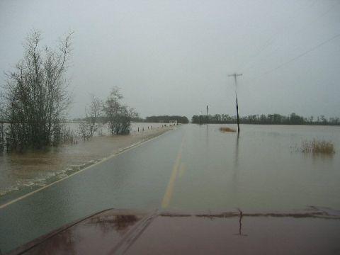 1991 Ford Explorer - Driving through a flooded rural road with water covering the sides and encroaching on the asphalt.