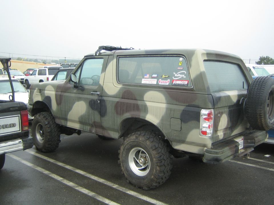 Camouflage-painted Ford Bronco SUV with oversized tires in a parking lot