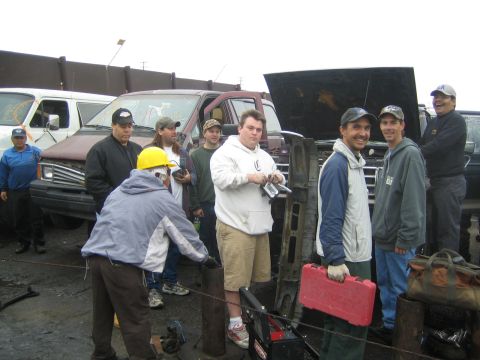 1990 Ford Bronco - group of men smiles for the camera around a red toolbox and seat frame, with vans and an open hood behind them in a yard.