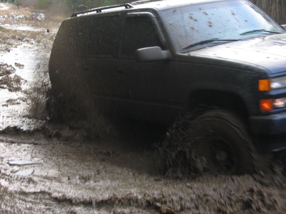 Dark SUV splashing through mud; Supermotors.net watermark visible