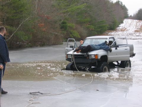 1976 GMC C/K Pickup - A Toyota pickup truck is stuck in ice with two people standing nearby.