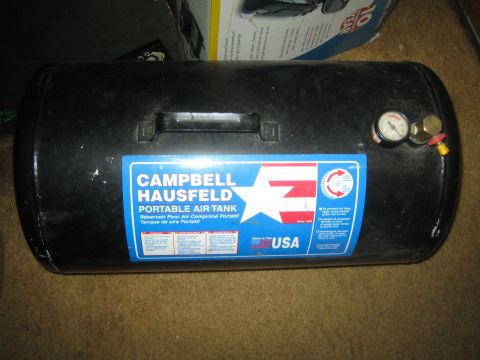 1990 Ford Bronco - black Campbell Hausfeld portable air tank with a pressure gauge and fill valve sits on a carpeted floor.