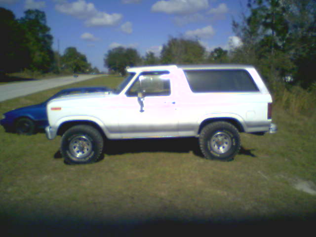 White SUV parked on grass next to a blue car. The SUV has a silver trim and tinted windows