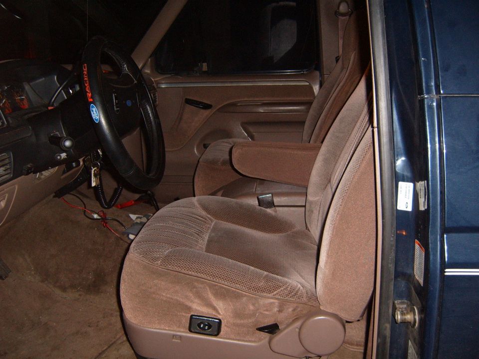 Tan cloth front seats and Ford Racing steering wheel in a blue truck, driver door open