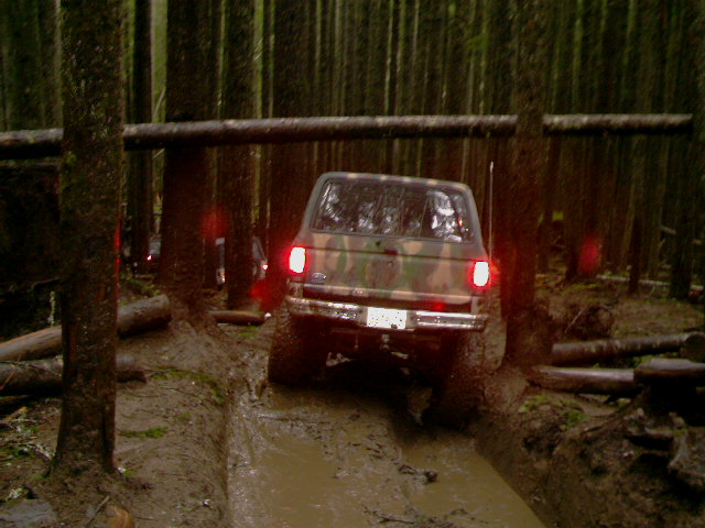 Camouflaged SUV navigating a muddy forest trail