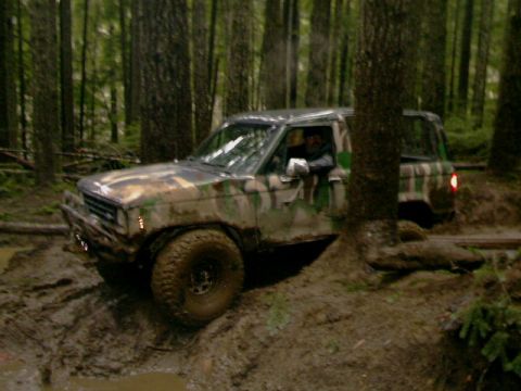 1987 Ford Bronco II - This vehicle is navigating a muddy trail surrounded by dense trees.