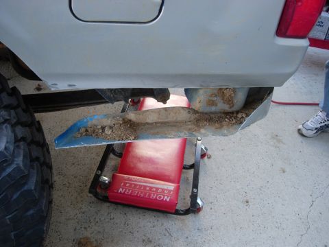 1995 Ford Bronco - The rear fender of a 1995 Ford Bronco has been trimmed, with dirt collected on a shovel underneath.