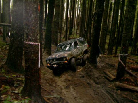 1987 Ford Bronco II - An off-road vehicle navigates a challenging path through a dense forest.
