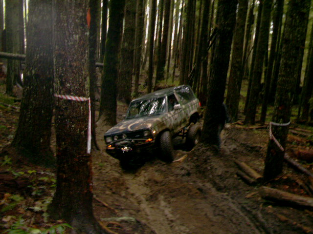 Camouflaged SUV driving on a muddy forest trail