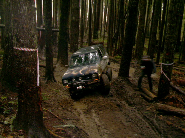 Off-road vehicle navigating a muddy forest trail
