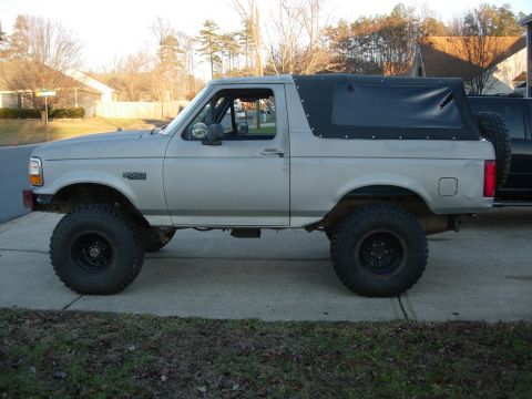 1995 Ford Bronco - This lifted SUV features a soft top and aggressive off-road tires, suggesting modifications for off-road use.