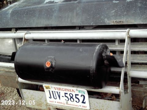 1988 Ford Bronco - A black auxiliary tank is mounted on the front bumper of a truck, obscuring the grille and headlights.