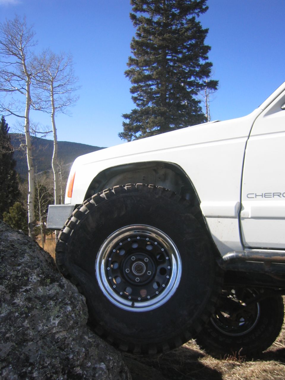 White Jeep Cherokee on a rock, front wheel turned