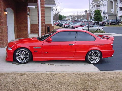 1995 BMW M3 - A red 1995 BMW M3 coupe is parked outside a brick building.