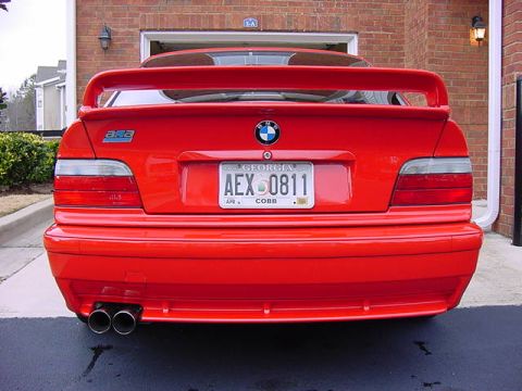 1995 BMW M3 - Rear view of a red 1995 BMW M3, showing its distinctive spoiler and dual exhaust.