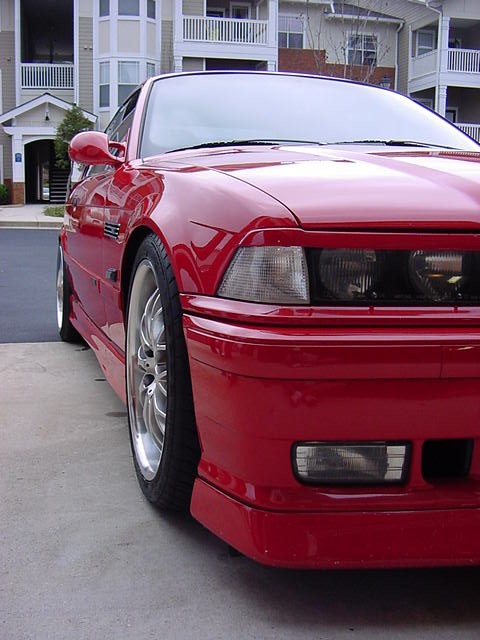 1995 BMW M3 - A red BMW coupe is parked on a concrete surface in front of an apartment complex.