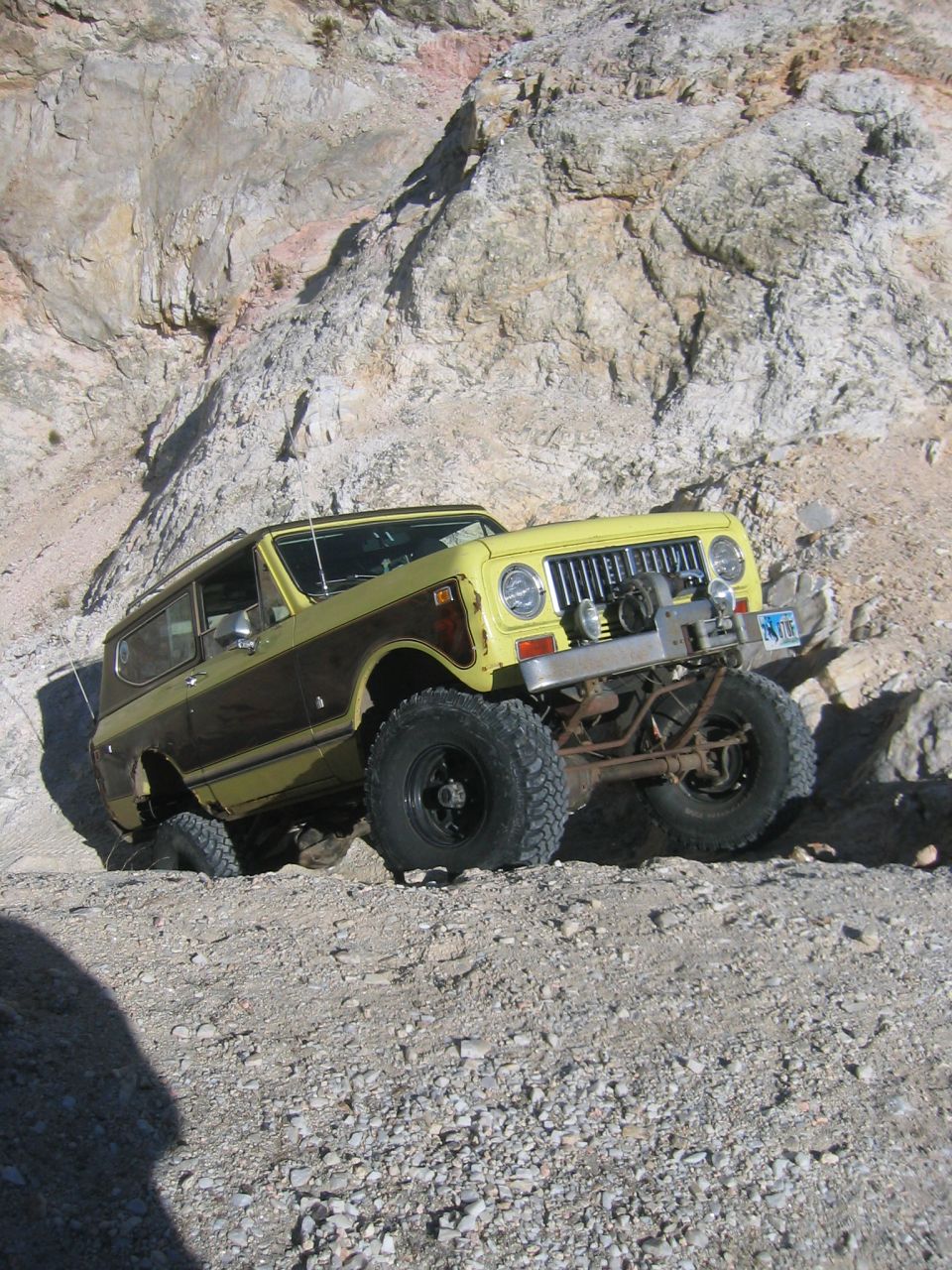 Yellow and brown SUV climbing a rocky incline