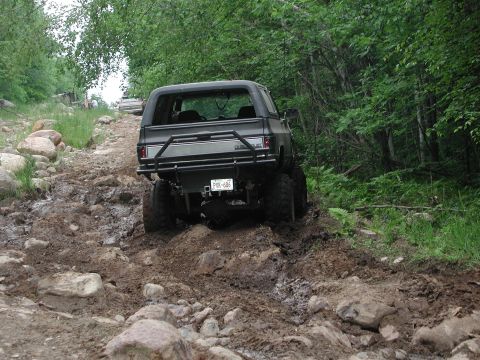 1977 Ford F-150 - This SUV is navigating a challenging off-road course with mud and rocks.