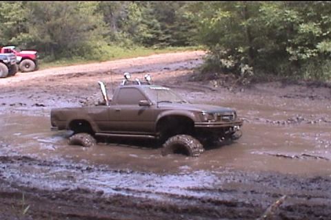 1977 Ford F-150 - Pickup truck is stuck in a mud pit with another vehicle in the background.