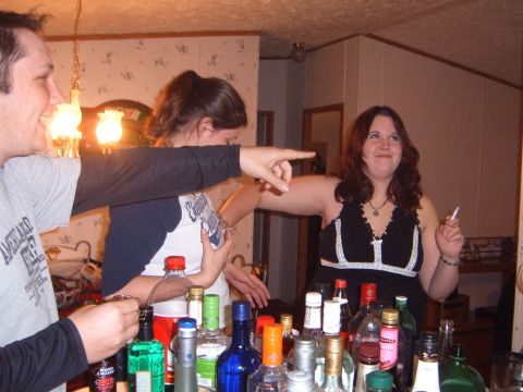 1988 Ford Bronco - People are gathered around a bar filled with bottles of alcohol, with one person pointing.