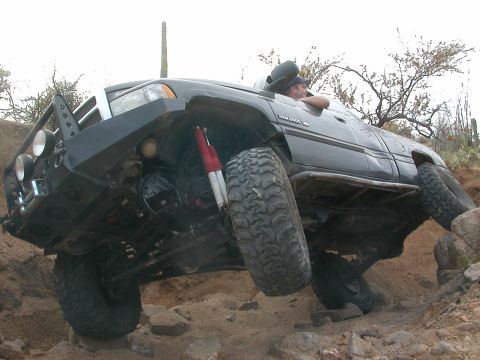 1984 Ford Bronco - An off-road vehicle with significant suspension articulation is shown traversing a challenging rocky landscape.