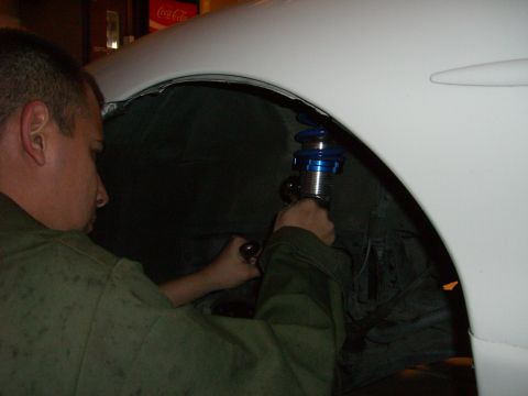 1996 Ford Probe - A person is working on the suspension of a white vehicle, adjusting a blue coilover shock absorber.