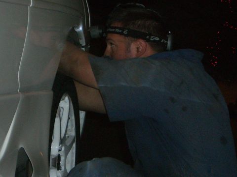 1996 Ford Probe - Mechanic working on a car's wheel well at night.