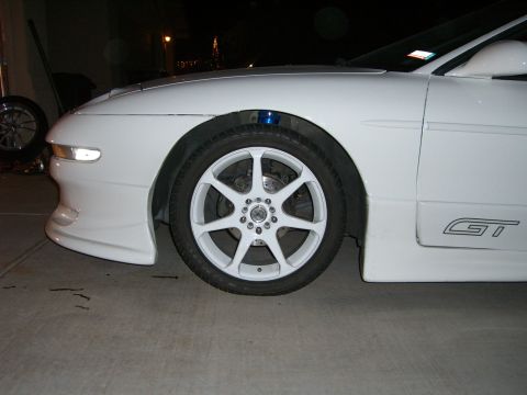 1996 Ford Probe - Close-up of a white car's front wheel and side skirt with GT badging.