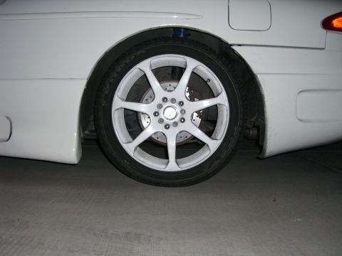 1996 Ford Probe - Close-up of a white car's rear wheel and fender assembly, highlighting the custom rim and tire.