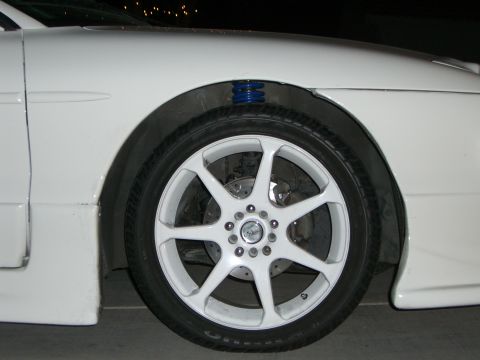 1996 Ford Probe - Close-up of a white car's front wheel and fender assembly, showing aftermarket modifications.