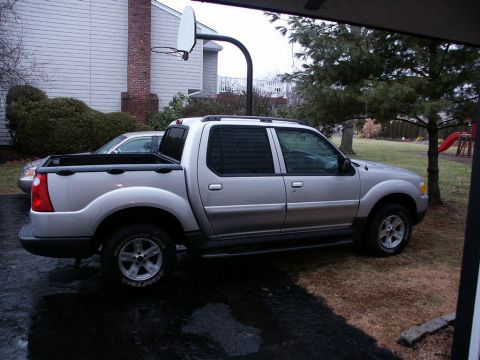 2001 Mercury Grand Marquis - A silver Ford Explorer Sport Trac pickup truck is parked in a driveway next to a house.