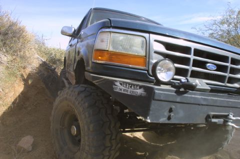1994 Ford Bronco - This 1994 Ford Bronco navigates a steep dirt incline, its front bumper displaying a humorous "SARCASM" sticker.