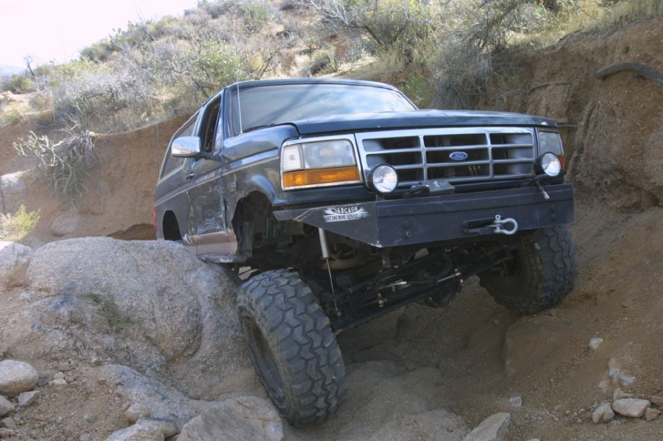 1994 Ford Bronco climbing over large rocks on a dirt trail