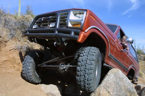 1994 Ford Bronco - This modified SUV navigates a rocky trail with its front end angled upwards.