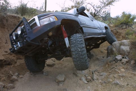 1994 Ford Bronco - Modified black Dodge Ram truck with large tires and custom bumper navigates a challenging rocky trail.