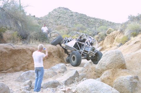 1994 Ford Bronco - This custom buggy is navigating a challenging rocky terrain, with a spectator capturing the moment.