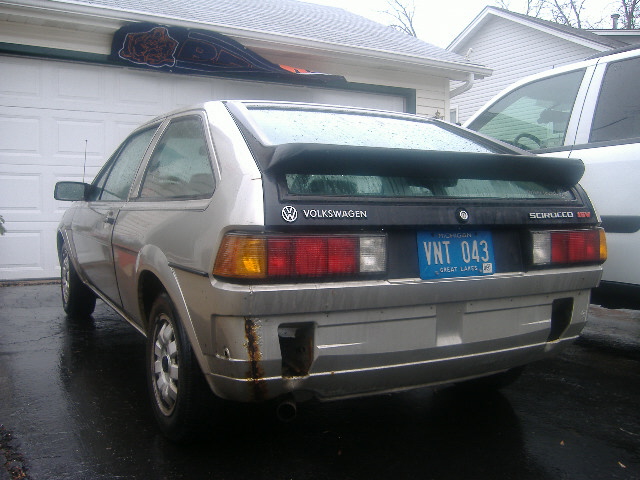 Silver VW Scirocco rear view with black spoiler, Michigan plate VNT 043, wet driveway