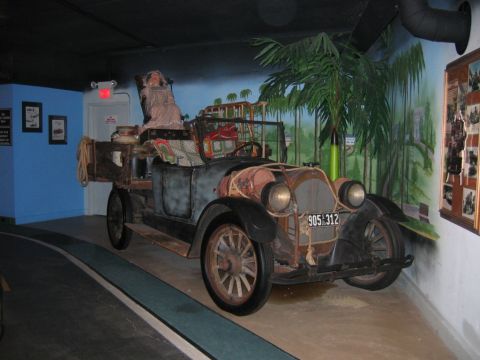 1985 Ford Crown Victoria LTD - This vintage vehicle, with a mannequin in the driver's seat, is displayed indoors with a painted jungle backdrop.