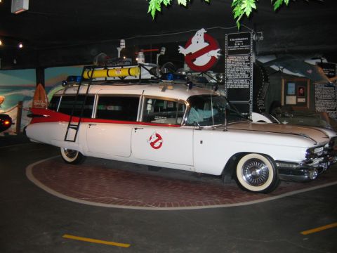1985 Ford LTD Crown Victoria - The iconic Ecto-1 from Ghostbusters, a modified 1959 Cadillac Miller-Meteor ambulance, is displayed indoors.