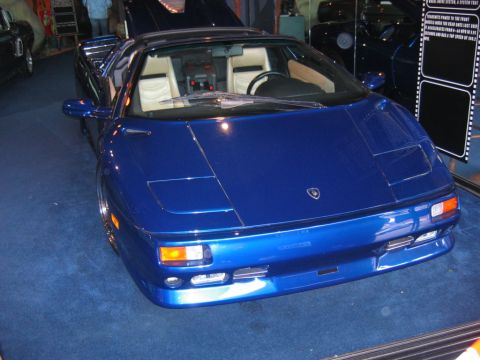 1985 Ford LTD Crown Victoria - Blue sports car with tan interior and pop-up headlights.
