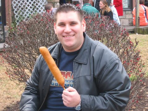 1985 Ford LTD Crown Victoria - Man with a corn dog smiles for the camera in front of a bare bush.