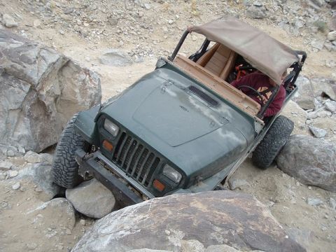 1989 Ford Bronco - A Jeep Wrangler is shown maneuvering through a challenging rocky terrain.