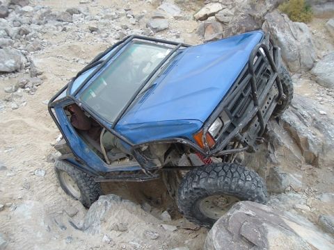1989 Ford Bronco - This modified off-road vehicle is navigating a difficult rocky terrain.