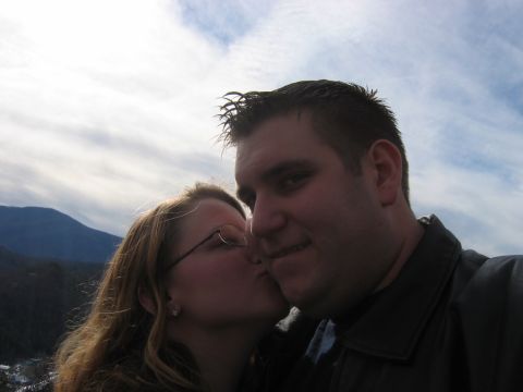 1985 Ford LTD Crown Victoria - A couple shares a kiss outdoors with a scenic mountain view.