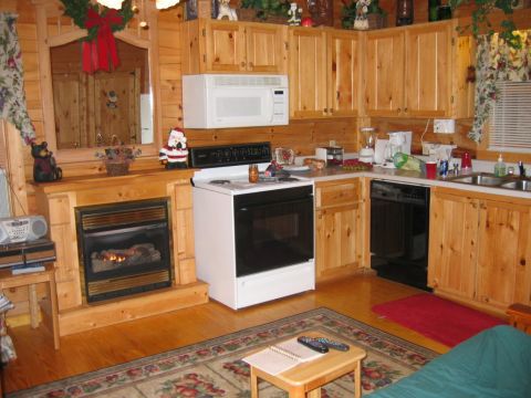 1985 Ford LTD Crown Victoria - A cozy log cabin interior features a fireplace, a white stove, and wooden kitchen cabinets.