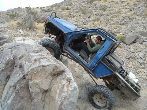 1989 Ford Bronco - A blue off-road vehicle navigates a rocky terrain, demonstrating its off-road capabilities.