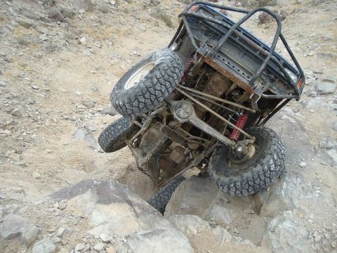 1989 Ford Bronco - This off-road vehicle is tilted precariously on rocky terrain, revealing its exposed undercarriage and suspension.
