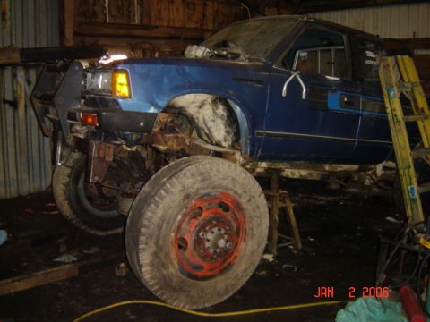 1982 Nissan Titan - This blue pickup truck, possibly from the early 1980s, is shown in a garage with large, off-road tires and appears to be undergoing modific…