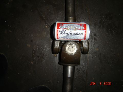 1982 Nissan Titan - A Budweiser can rests on a vehicle's driveshaft universal joint, with a date stamp visible in the corner.