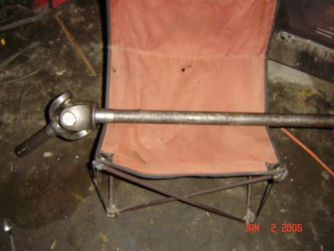 1982 Nissan Titan - A driveshaft with a U-joint is shown resting on a folding chair, with a "Supermotors.net" watermark visible.